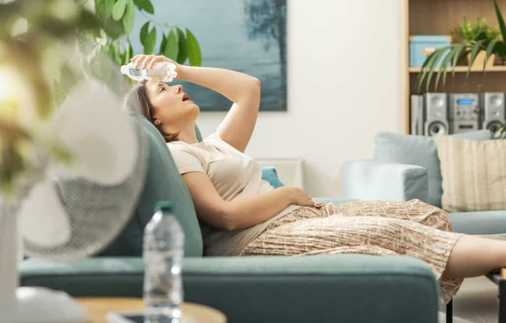 Woman resting with water bottle in warm room